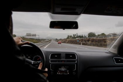 Pogled iz unutrašnjosti automobila na vozača i put ispred vozila.