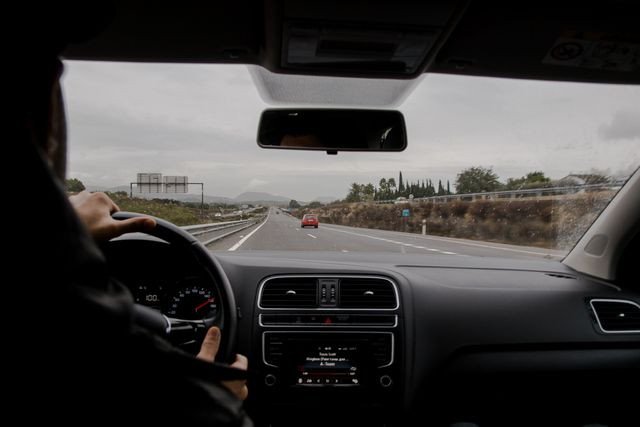 Pogled iz unutrašnjosti automobila na vozača i put ispred vozila.
